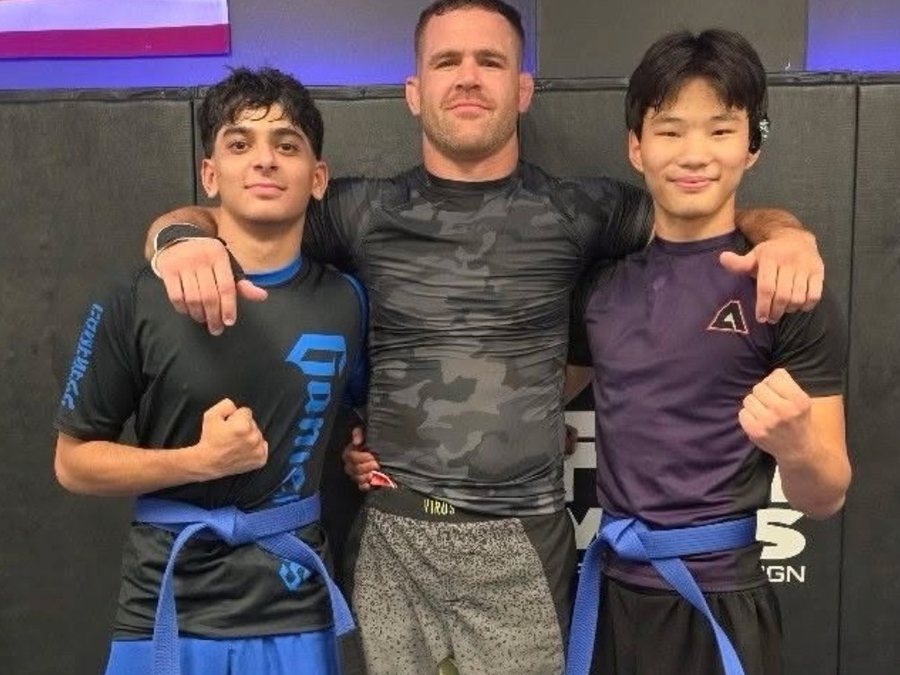Jonathan Di Lorenzo on the mats with two students wearing blue belts